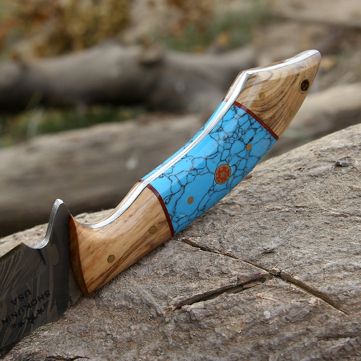 Knife with wooden handle and blue inlay on a rock