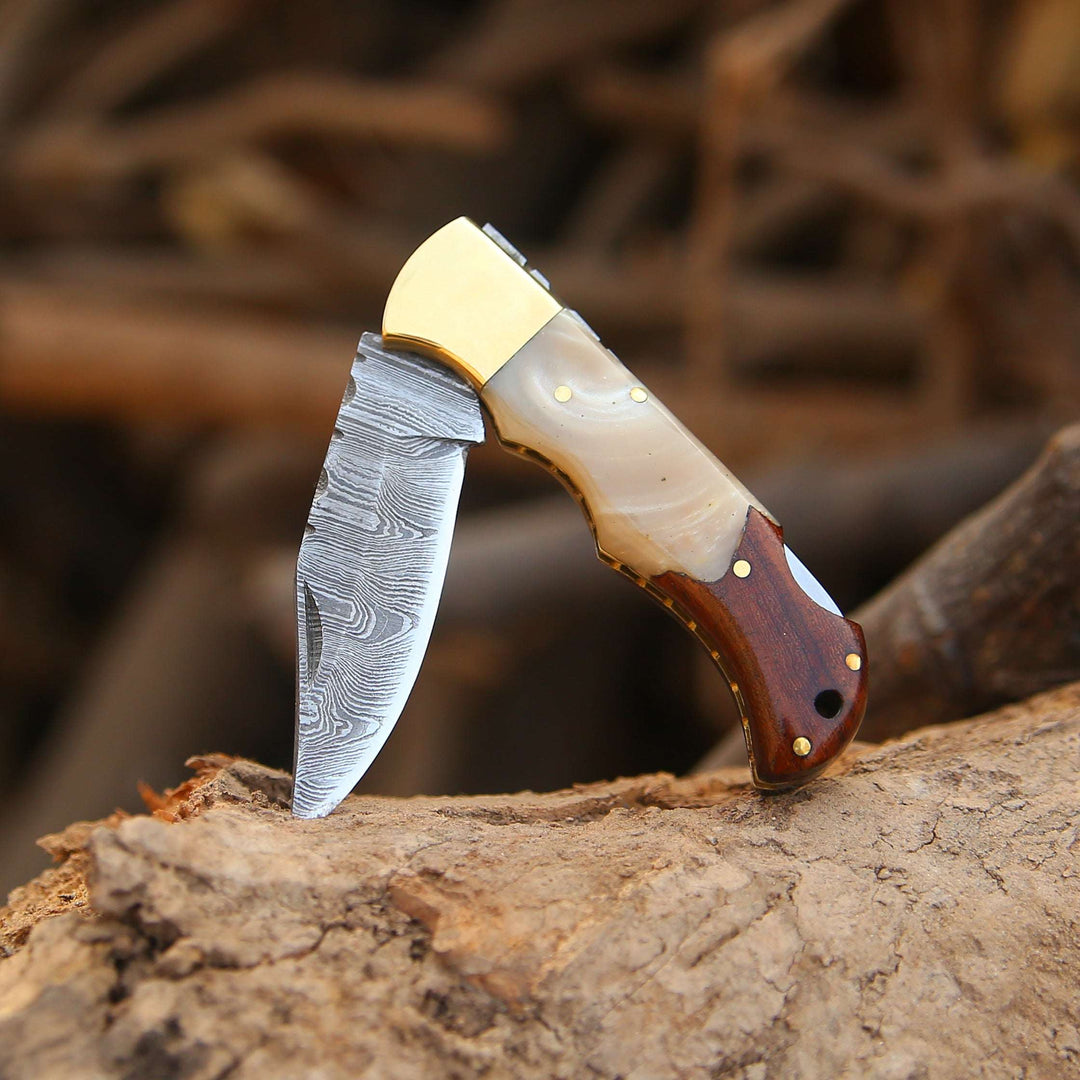 Handcrafted knife with a wooden handle and gold accents on a wooden surface