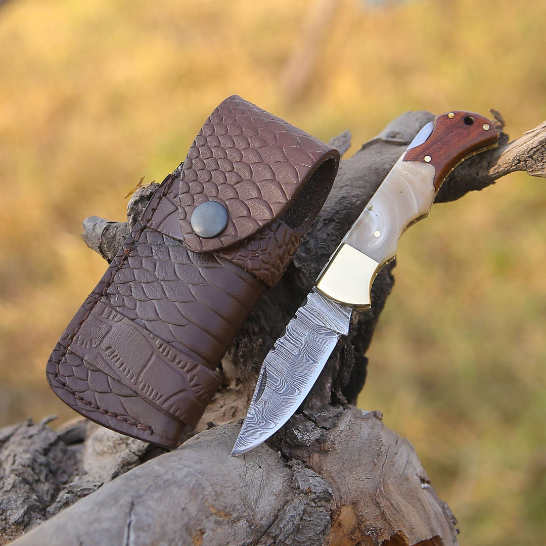 Knife with wooden handle and leather sheath on a wooden surface with blurred natural background