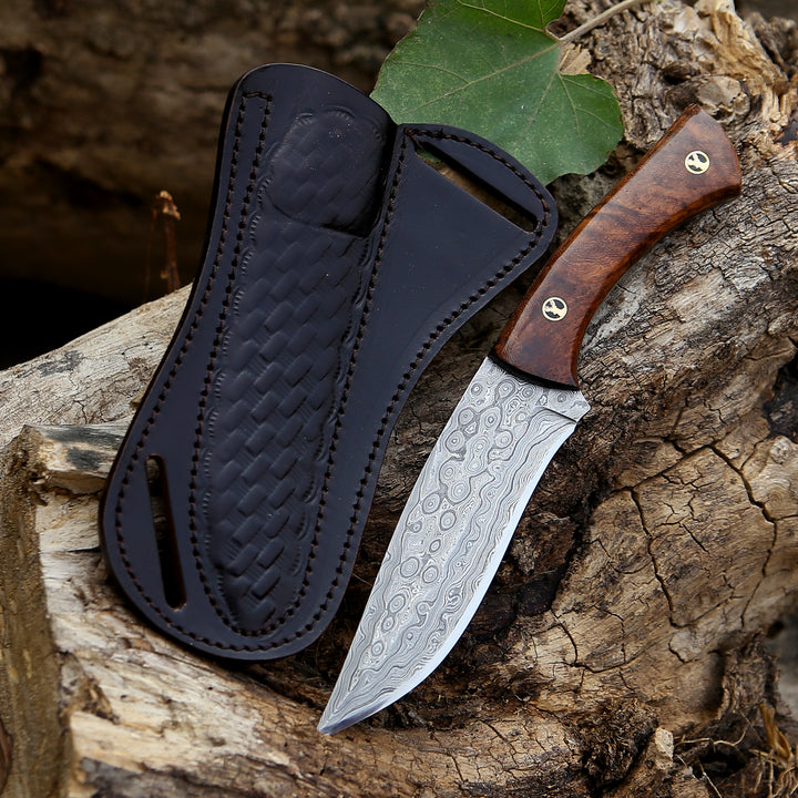 Knife with wooden handle and black leather sheath on a wooden surface