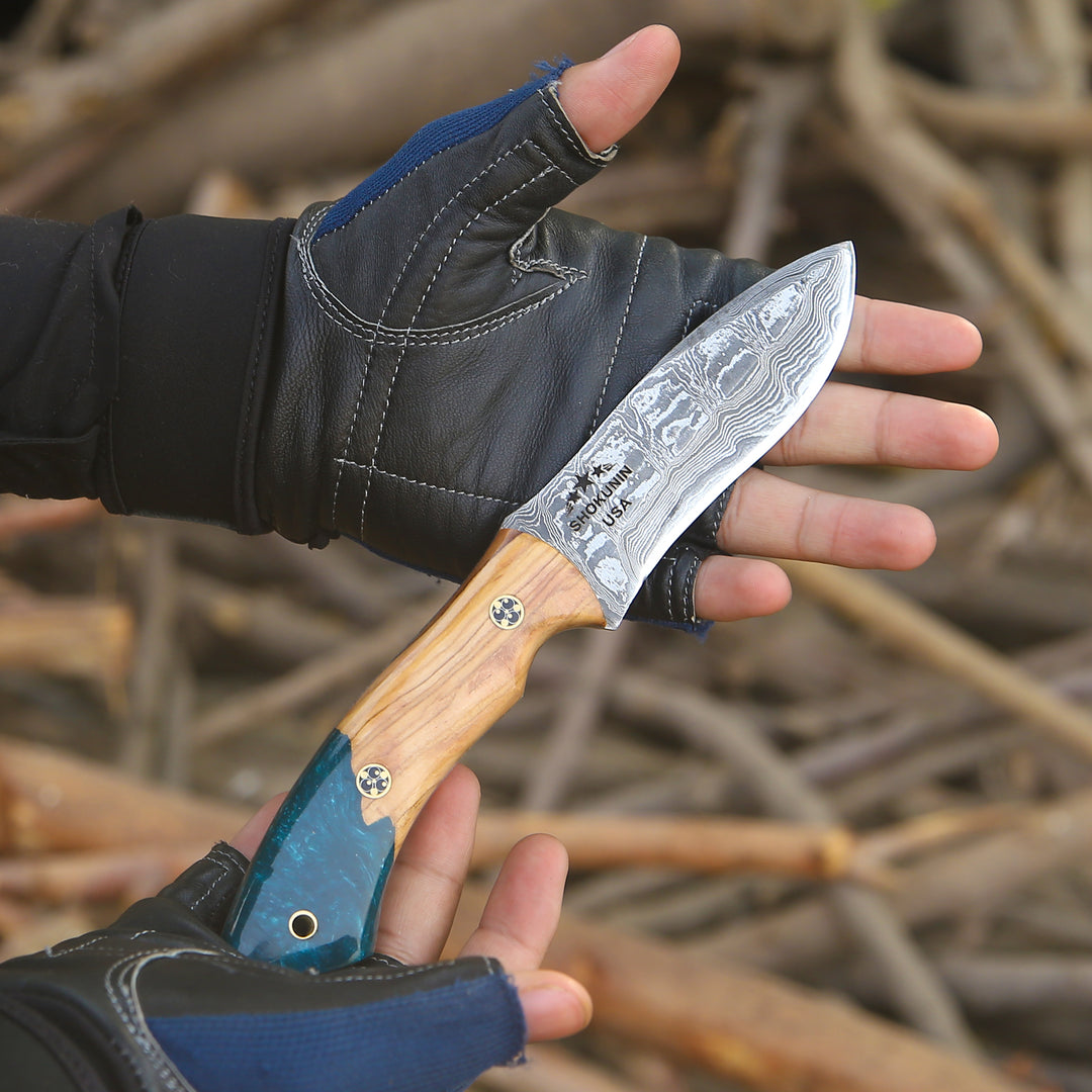 Hand holding a knife with a wooden handle and metal blade against a natural background