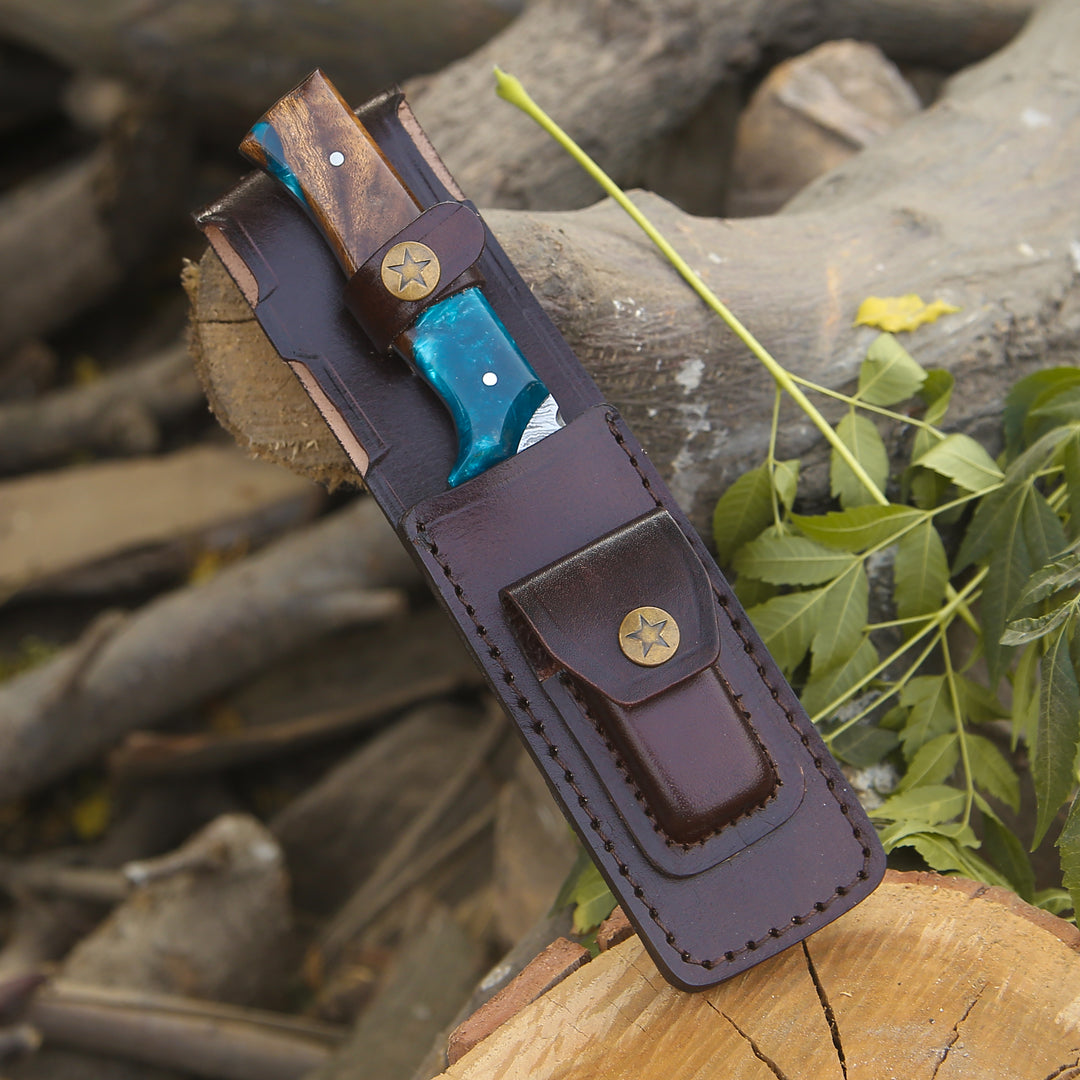 Leather knife sheath with blue blade on a wooden log background
