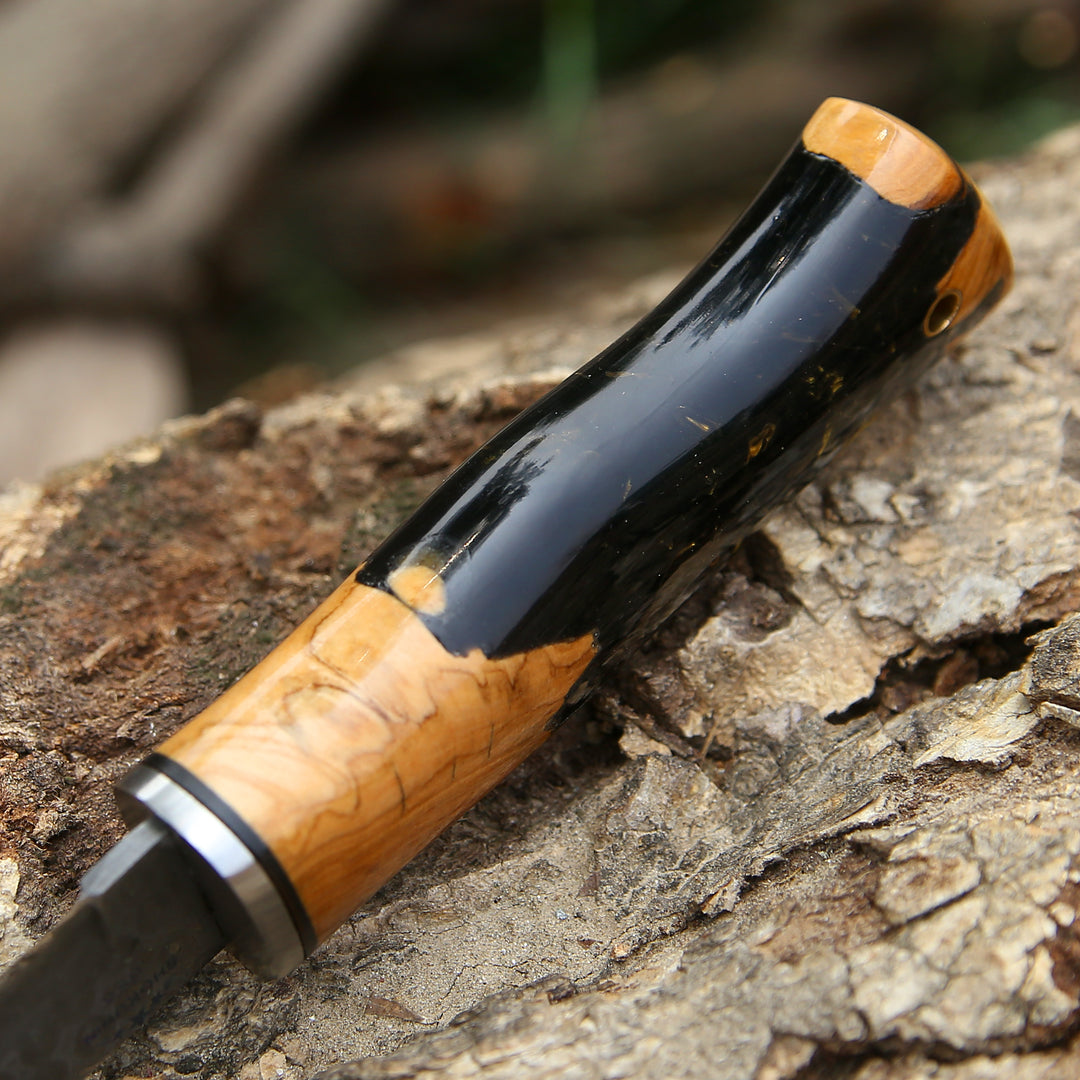 Wooden-handled knife with black blade on a textured surface