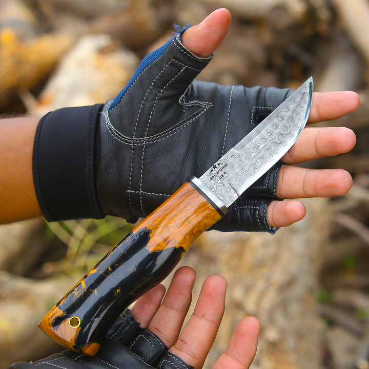 Hand holding a knife with a wooden handle and metal blade, wearing a black glove.