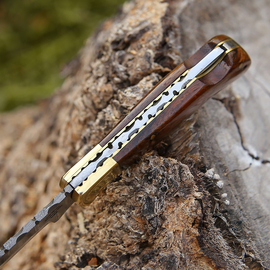 Decorative knife with wooden handle and gold accents on a textured surface