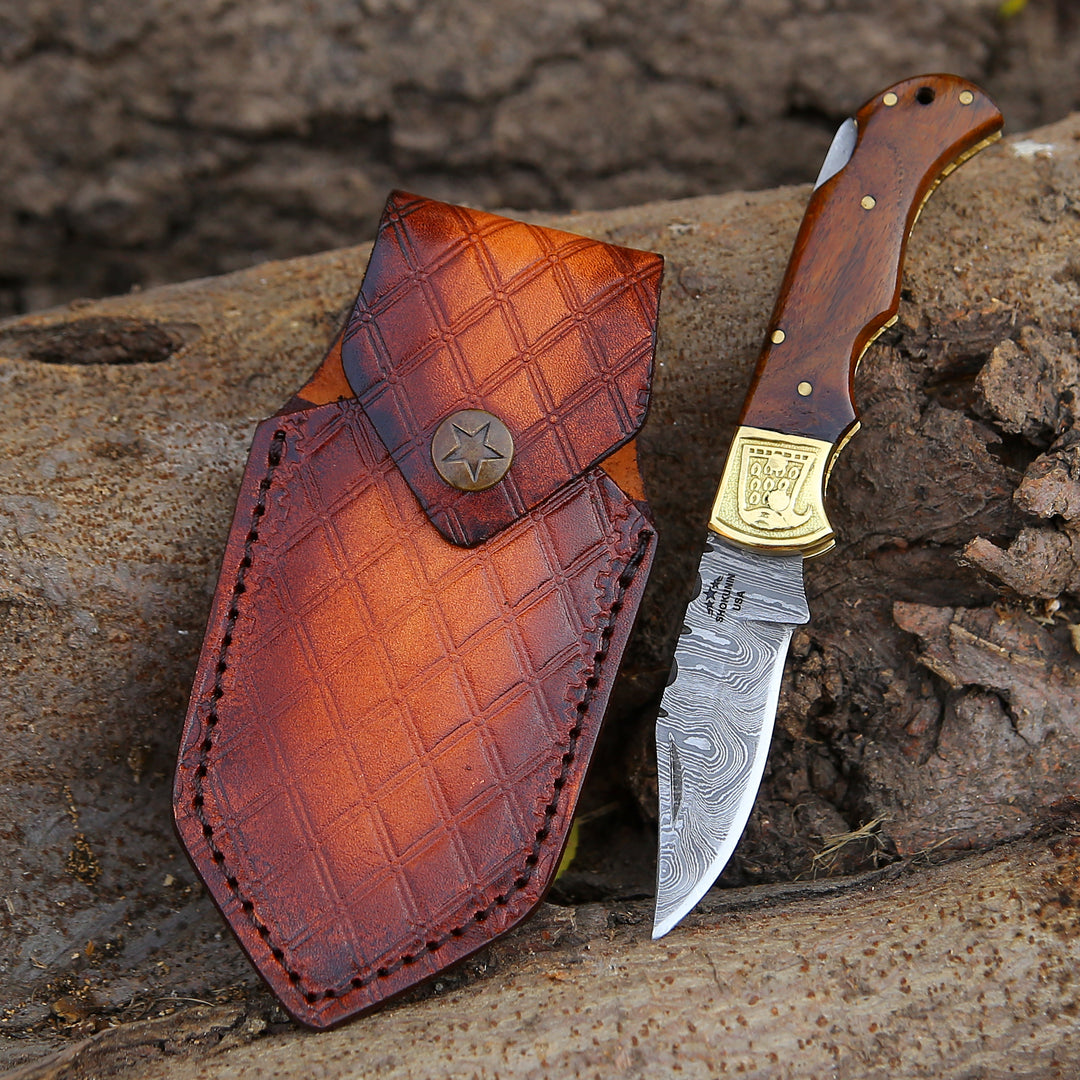 Knife with wooden handle and leather sheath on a rocky surface