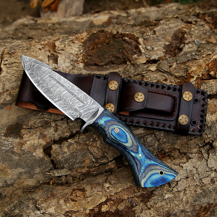 Knife with a blue handle and damascus blade in a leather sheath on a wooden surface